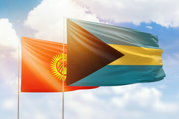 Sunny blue sky and flags of bahamas and kyrgyzstan