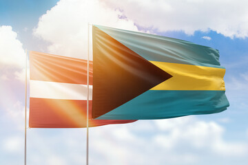 Sunny blue sky and flags of bahamas and latvia