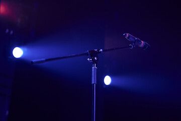Professional stage microphone in a bright spotlight on a dark background. High quality photo