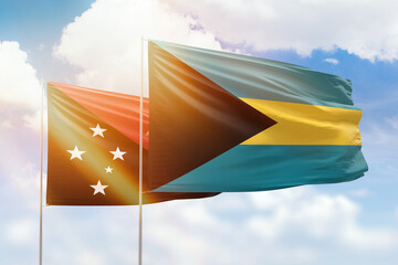 Sunny blue sky and flags of bahamas and papua new guinea