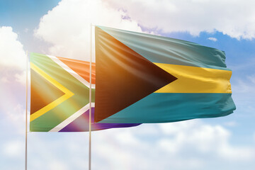 Sunny blue sky and flags of bahamas and south africa