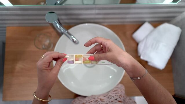 Woman placing in a pillbox all the medicines she takes every day.