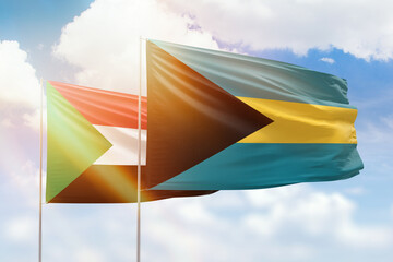 Sunny blue sky and flags of bahamas and sudan