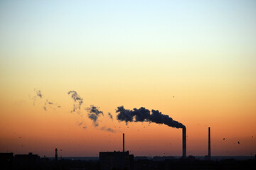 Obraz premium Smoke coming from factory's chimney at sunset