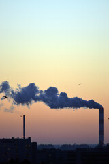 Obraz premium Smoke coming from factory's chimney at sunset