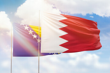 Sunny blue sky and flags of bahrain and bosnia