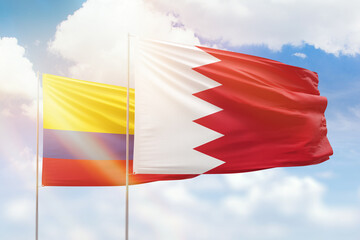 Sunny blue sky and flags of bahrain and colombia