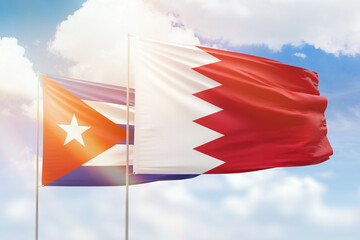 Sunny blue sky and flags of bahrain and cuba
