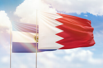 Sunny blue sky and flags of bahrain and el salvador