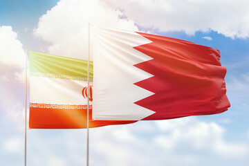 Sunny blue sky and flags of bahrain and iran