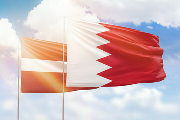 Sunny blue sky and flags of bahrain and latvia