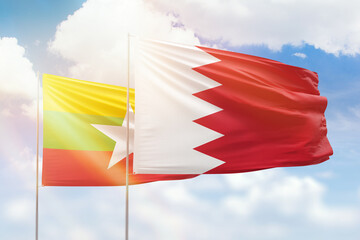 Sunny blue sky and flags of bahrain and myanmar