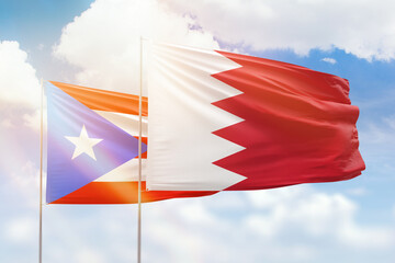 Sunny blue sky and flags of bahrain and puerto rico
