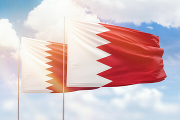 Sunny blue sky and flags of bahrain and qatar