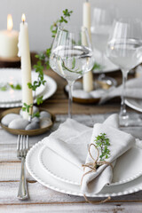 Rustic zero waste wedding decor with natural elements. Wooden table, candles, linen napkins, branches with green leaves. Eco-friendly decoration for the special dinner. Romantic and cozy place