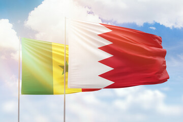 Sunny blue sky and flags of bahrain and senegal
