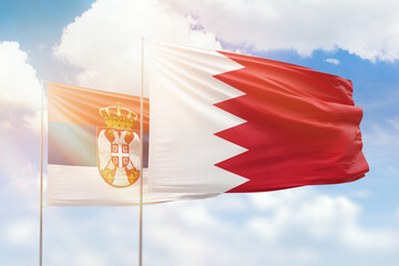 Sunny blue sky and flags of bahrain and serbia