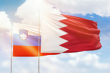 Sunny blue sky and flags of bahrain and slovenia