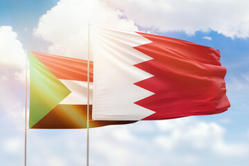 Sunny blue sky and flags of bahrain and sudan