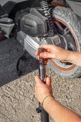 A car mechanic inserts a metal damper spring into the shock absorber of the front fork of a...