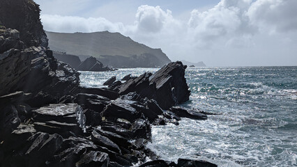 des rochers noirs en bord d'océan sous un ciel bleu