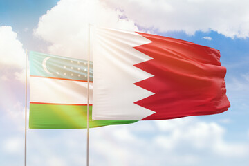 Sunny blue sky and flags of bahrain and uzbekistan