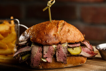 Pastrami sandwich on rye bread served with pickles and mustard sauce. Tasty sandwich with french...
