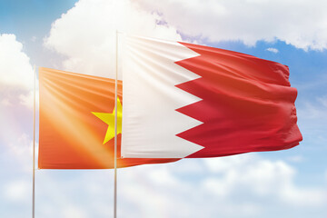 Sunny blue sky and flags of bahrain and vietnam