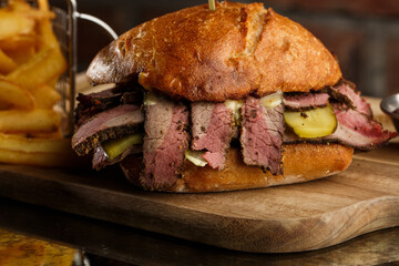 Pastrami sandwich on rye bread served with pickles and mustard sauce. Tasty sandwich with french...