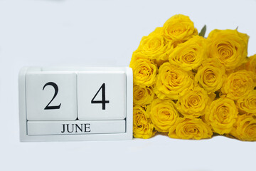 Wooden, white calendar June 24 , bouquet of yellow roses lie next to it . The concept of holidays, important date, event . High quality photo