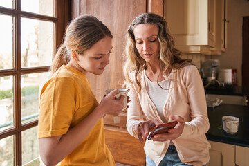 Teenage girl looking at the smartphone screen while her mother showing something to her
