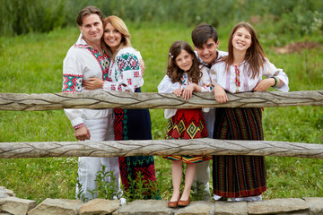 Front view of a beautiful family with kids in traditional clothes posing in a countryside.