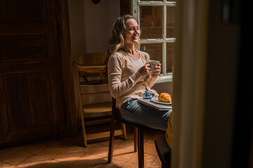 Woman enjoying her morning coffee with croissant while chatting with her daughter