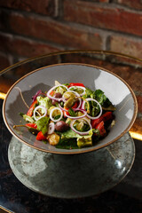 Greek salad with fresh vegetables: tomato, cucumber, red bel pepper, lettuce, onion, olives and cheese. Close-up on a white round plate on a wooden background. Salad menu with ingredients