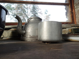 Fototapeta na wymiar Old dilapidated aluminum teapot and pot standing on a dilapidated wooden table.