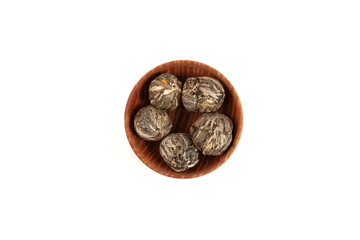 Green tea with lilies and jasmine. Tea leaves with a floral aroma in wooden bowl, top view