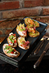 Bruschettas with vegetables. Start dishes with cherry tomatoes, avocado, cream cheese and shrimps. Food composition, tasty italian meal