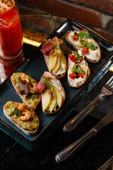 Bruschettas with vegetables. Start dishes with cherry tomatoes, avocado, cream cheese and shrimps. Food composition, tasty italian meal
