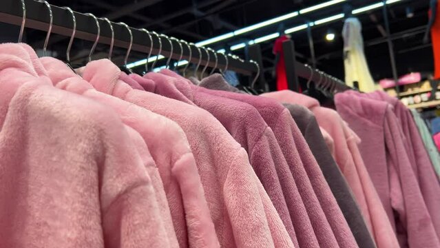 Rows of woman`s pink terry bathrobes hanging on a hangers in a store
