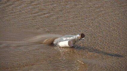 A message in a bottle washed up on the beach by waves