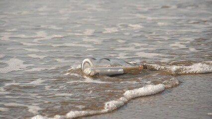 A message in a bottle washed up on the beach by waves