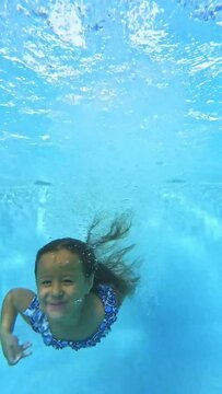 video from under the water of a girl jumping into the pool