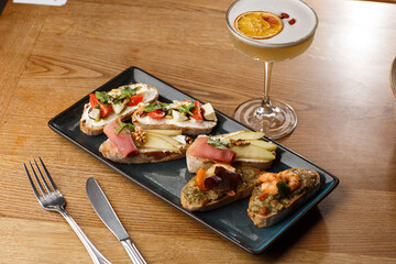 Bruschettas with vegetables. Start dishes with cherry tomatoes, avocado, cream cheese and shrimps. Food composition, tasty italian meal