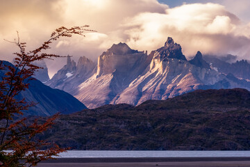 cuernos de las torres del Paine, octava maravilla del mundo, Magallanes, entre montes y nubes atardecer entre montañas con hojas y ramas de arboles otoñales 