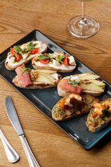 Bruschettas with vegetables. Start dishes with cherry tomatoes, avocado, cream cheese and shrimps. Food composition, tasty italian meal