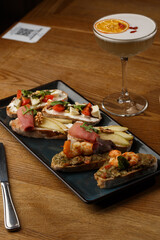 Bruschettas with vegetables. Start dishes with cherry tomatoes, avocado, cream cheese and shrimps. Food composition, tasty italian meal