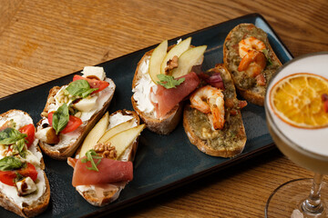 Bruschettas with vegetables. Start dishes with cherry tomatoes, avocado, cream cheese and shrimps. Food composition, tasty italian meal