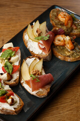 Bruschettas with vegetables. Start dishes with cherry tomatoes, avocado, cream cheese and shrimps. Food composition, tasty italian meal