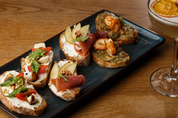 Bruschettas with vegetables. Start dishes with cherry tomatoes, avocado, cream cheese and shrimps. Food composition, tasty italian meal