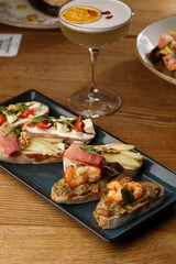 Bruschettas with vegetables. Start dishes with cherry tomatoes, avocado, cream cheese and shrimps. Food composition, tasty italian meal